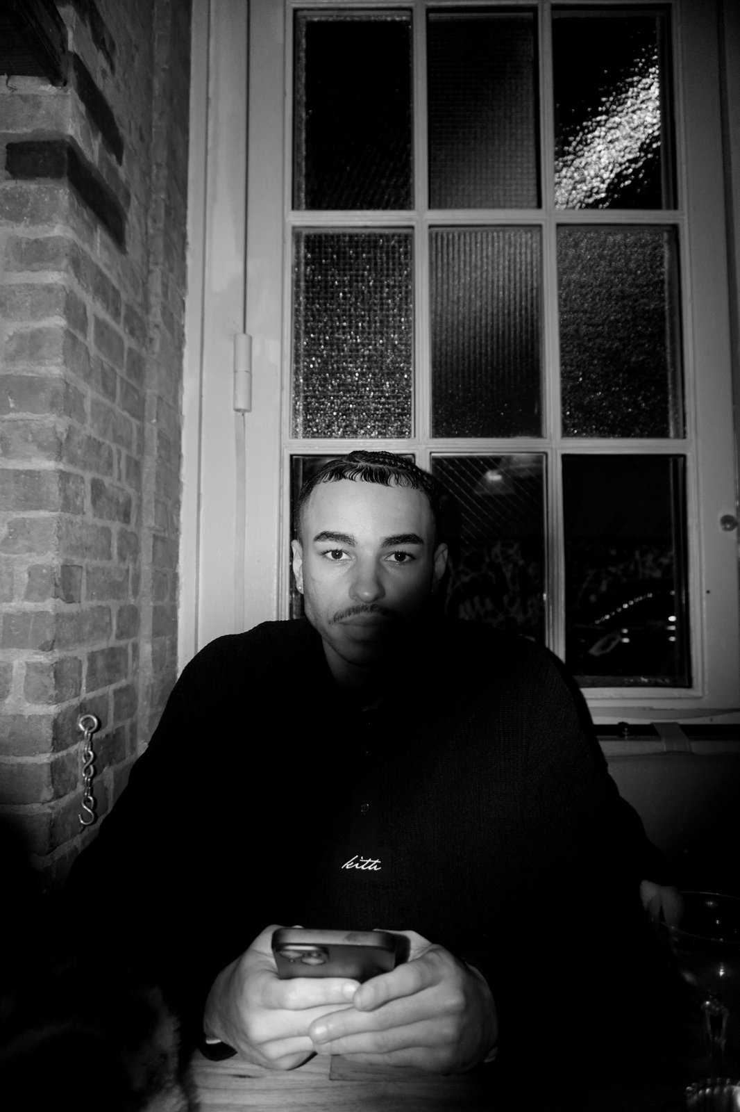 Black-and-white portrait of Jourdan Joseph at a table by a window