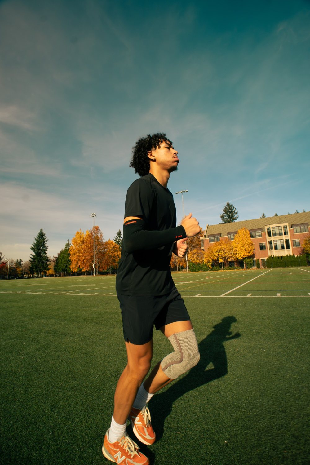Jayo running on a field in Incrediwear knee and arm sleeves