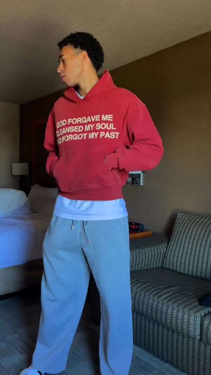 Jayo in a red hoodie and light-blue sweats in a Calgary hotel room